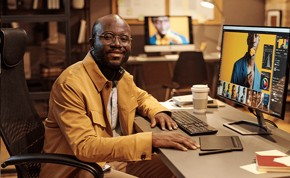 Graphic designer at desk looking at camera