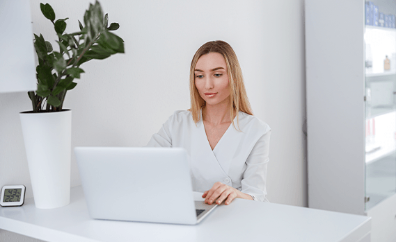 Beauty technician working on laptop at salon